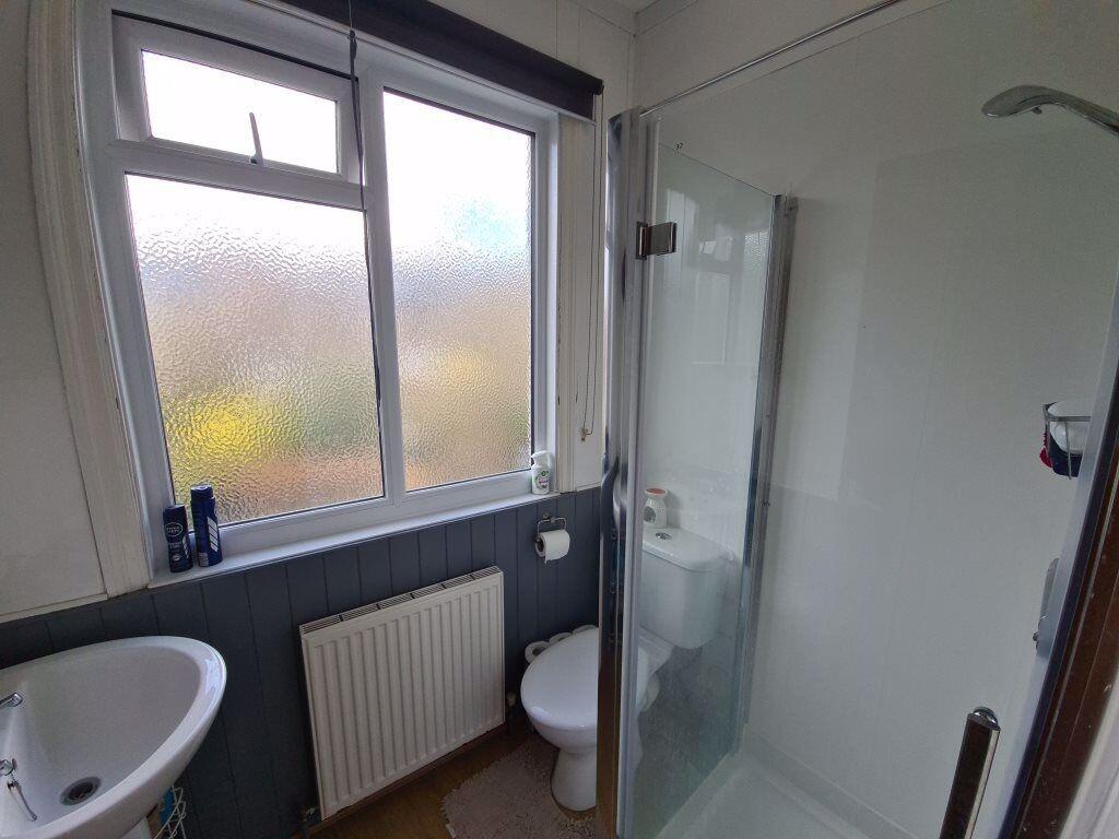 Bright, modern bathroom with a corner glass sho...