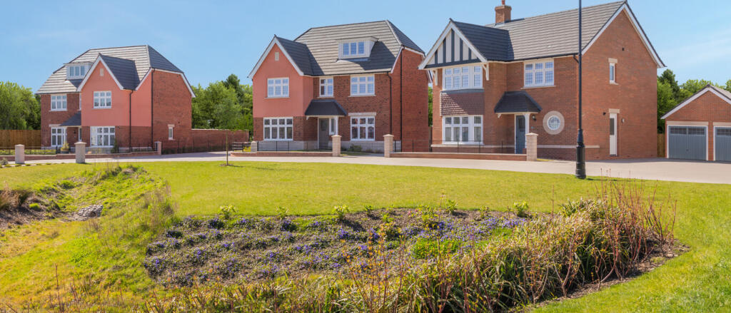 Modern brick and pink houses with large windows and landscaped gardens under a clear blue sky at Blo