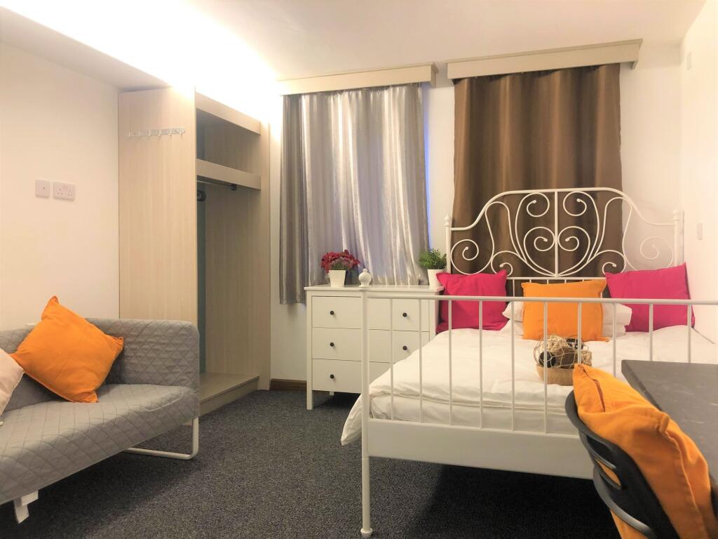A cozy double bedroom featuring a stylish white...