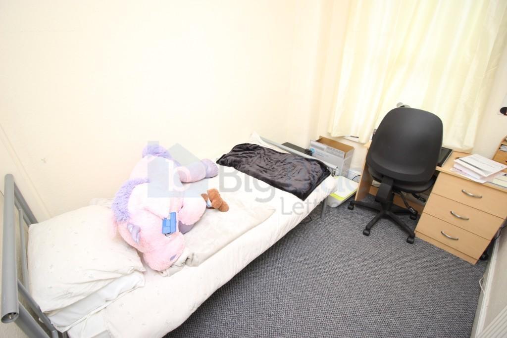 A cozy single bedroom featuring a single bed wi...