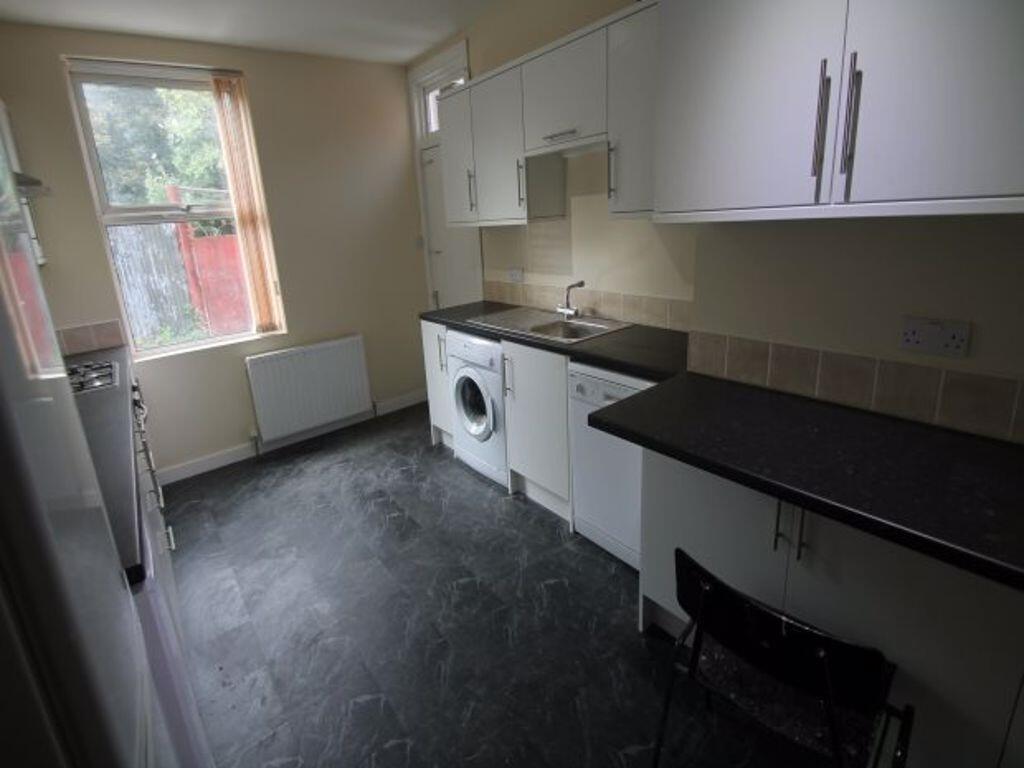 Neat galley kitchen with white cabinetry, integ...