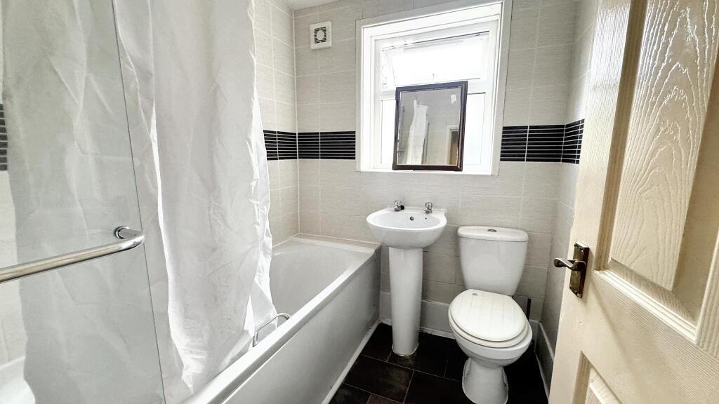 A clean and tidy bathroom featuring a bathtub, ...