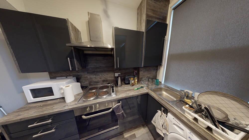 Well-equipped modern kitchen with dark cabinetr...