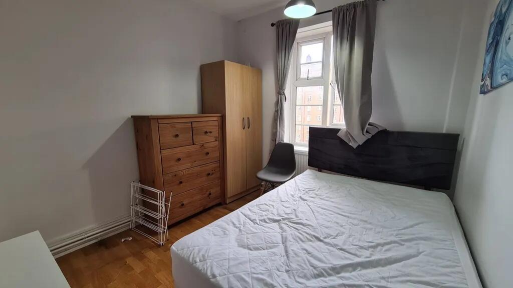 Bright double bedroom with a large window letti...