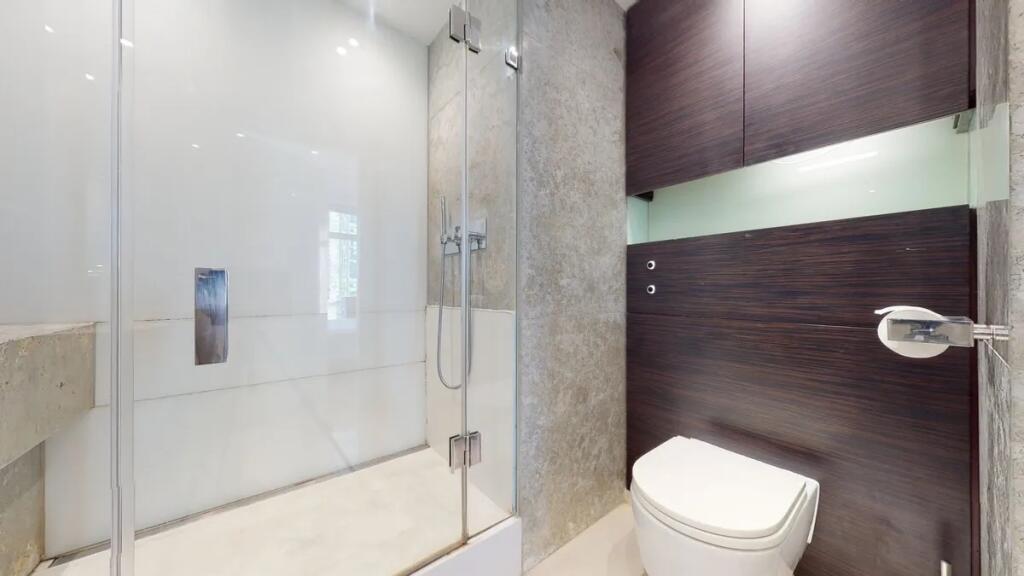 Modern bathroom suite featuring a sleek glass-e...