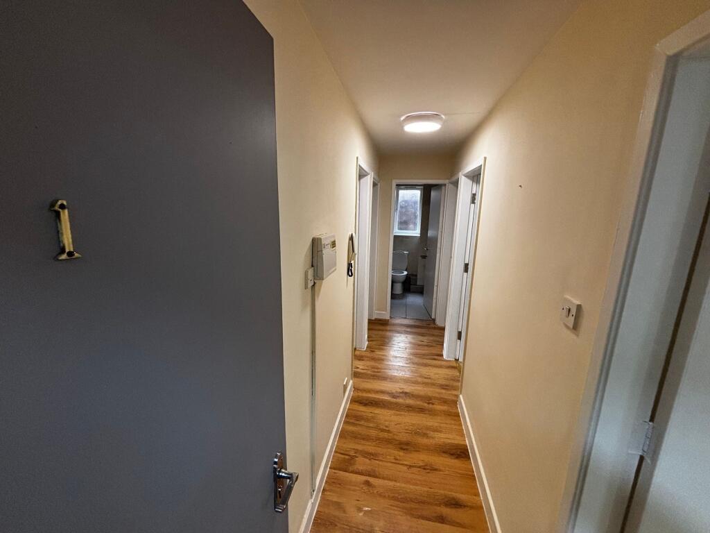A bright, clean bathroom with a toilet and wind...