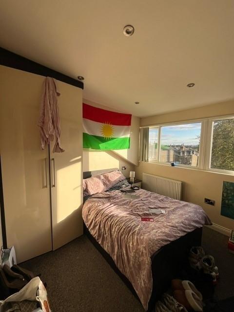 Sunny upper-floor bedroom with a bed positioned...