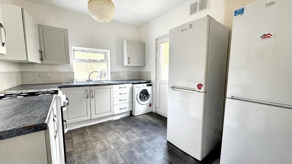 A well-lit, modern kitchen featuring white cabi...