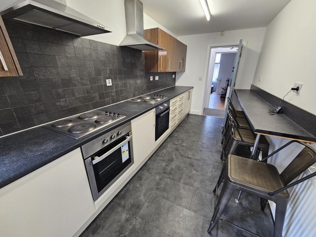 A modern galley kitchen featuring sleek black c...