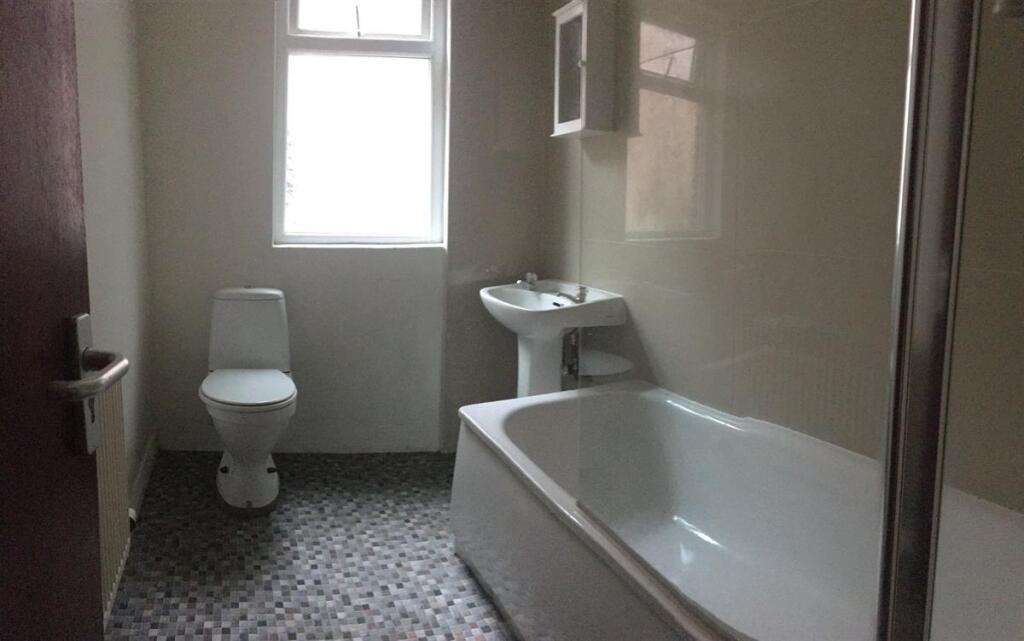 Clean, modern bathroom with a bathtub and separ...