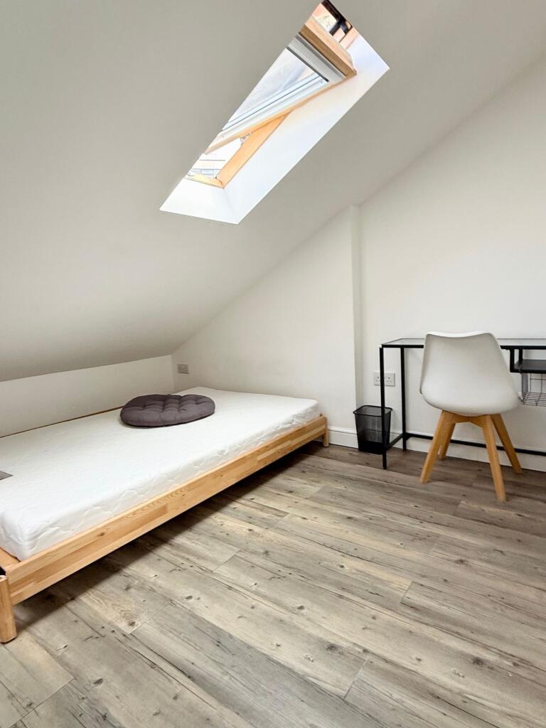 A simple, clean bedroom with a single bed under...