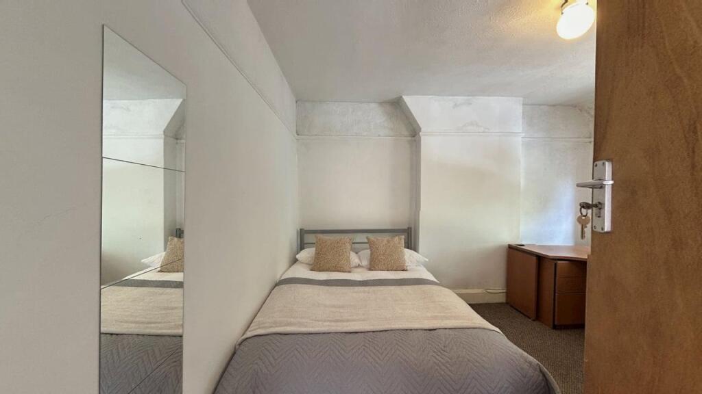 A cozy double bedroom featuring a neatly made b...