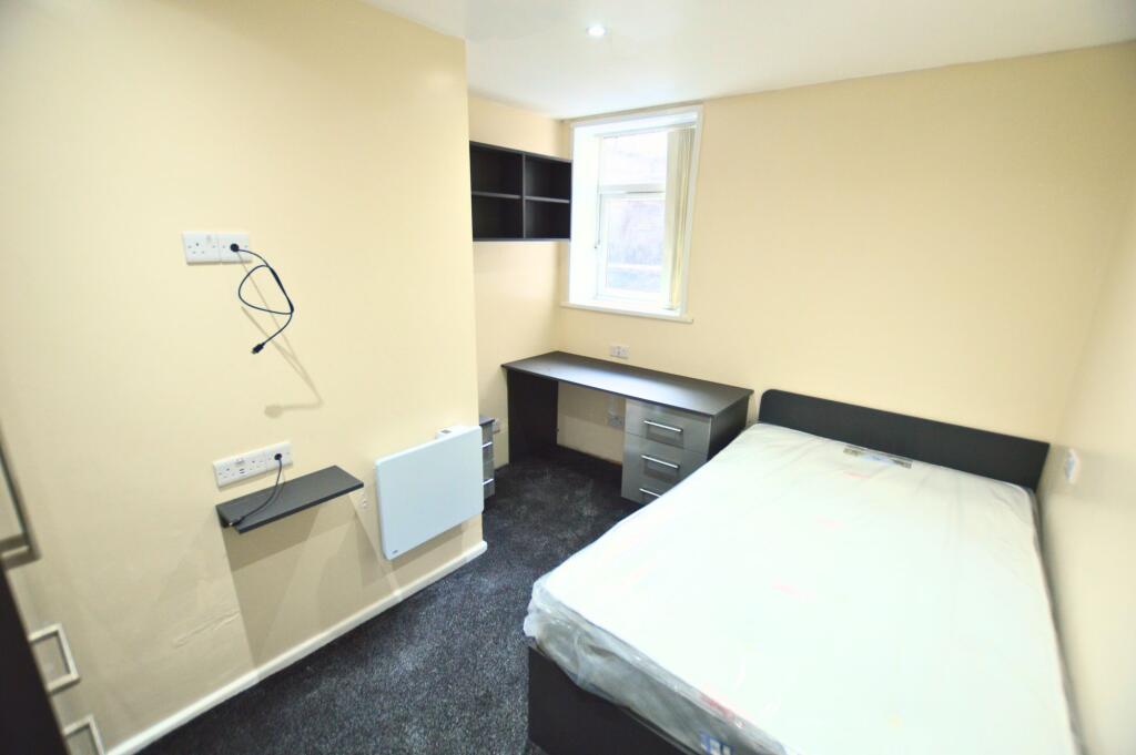 Compact and clean student bedroom featuring a c...