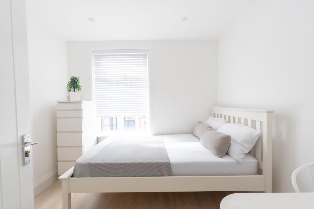 Bright and tidy double bedroom featuring a whit...