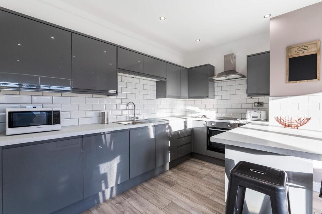 Bright modern kitchen with grey Shaker-style ca...