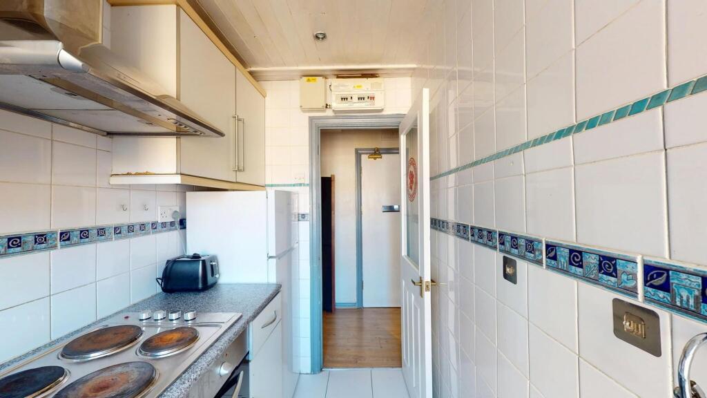A functional and tidy kitchen with white tiled ...