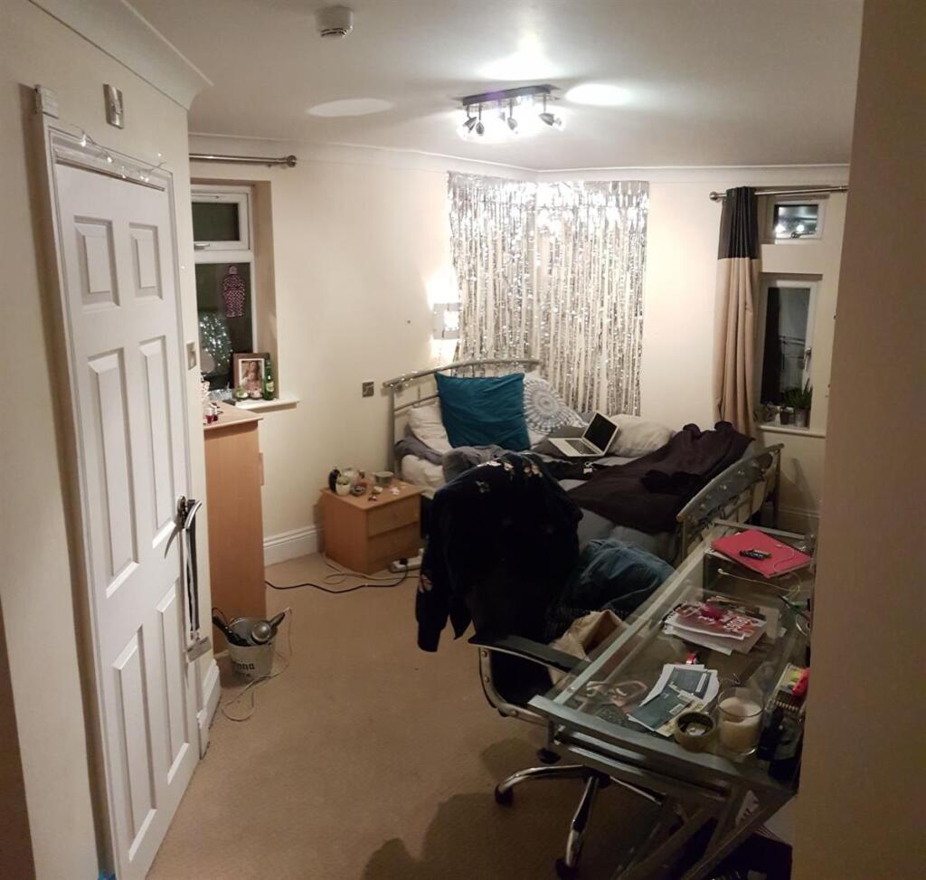 Cozy single bedroom featuring a practical desk ...