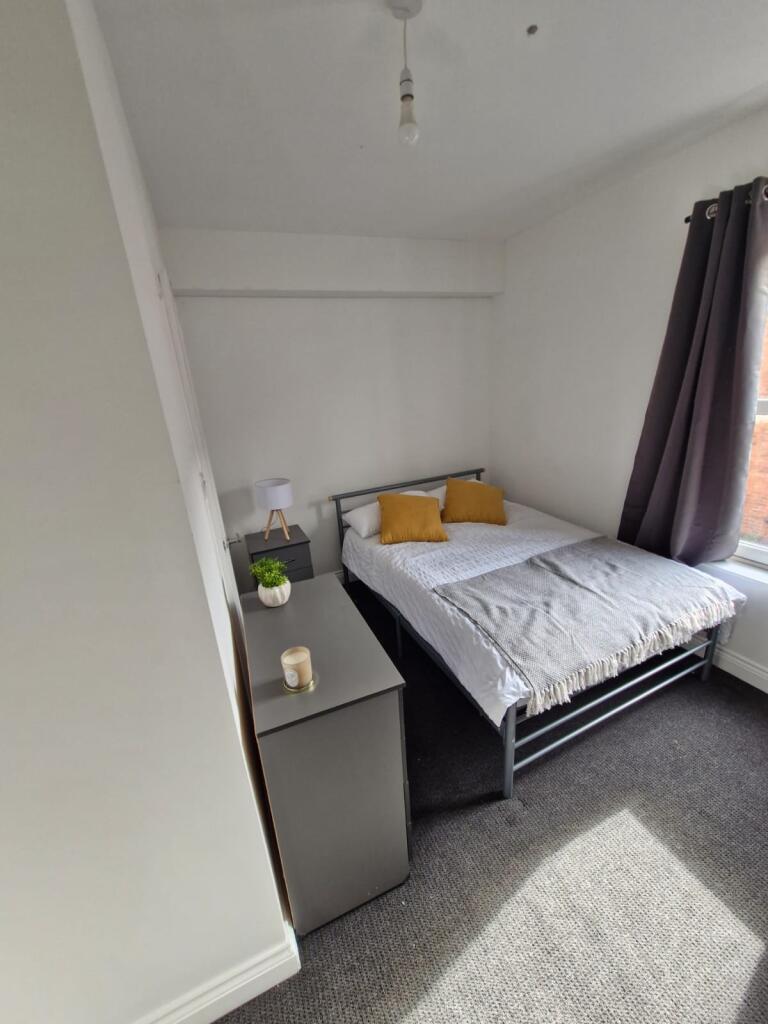 A neat and bright bedroom featuring a comfortab...