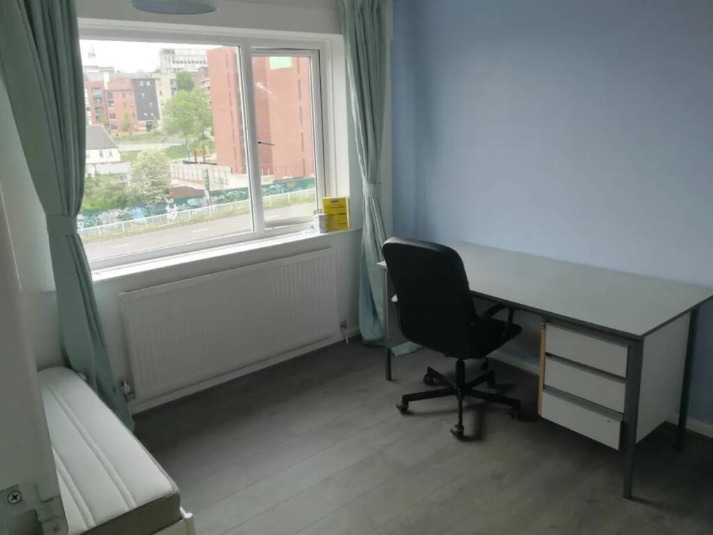 A bright, tidy single bedroom with a large wind...