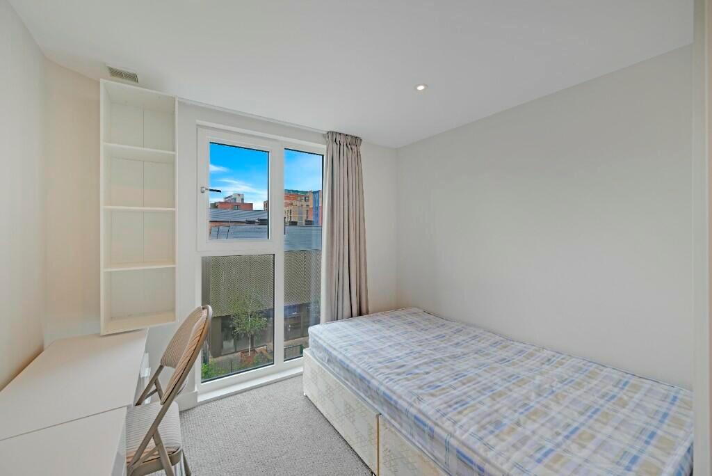 A neat and well-lit single bedroom featuring a ...