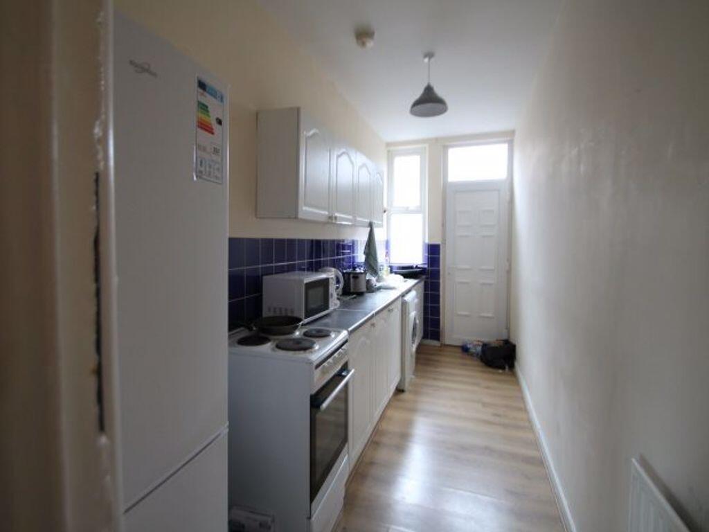 A compact, well-lit kitchen space with white ca...