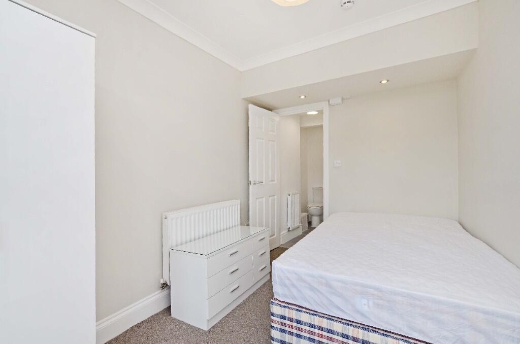 A neat and tidy single bedroom featuring a comf...