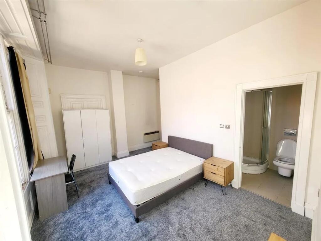 Bright and spacious master bedroom with a comfo...