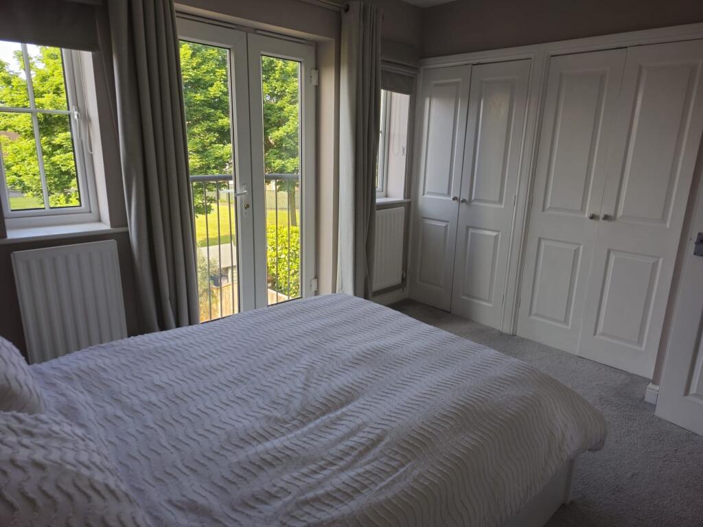 A bright double bedroom featuring large French ...