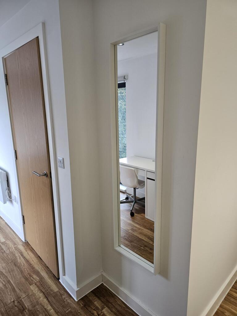A clean, modern hallway featuring wood flooring...