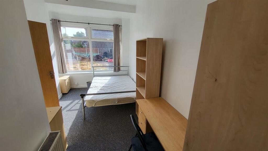 A bright single bedroom featuring a large windo...