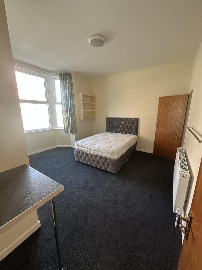 A cozy single bedroom featuring a large window ...