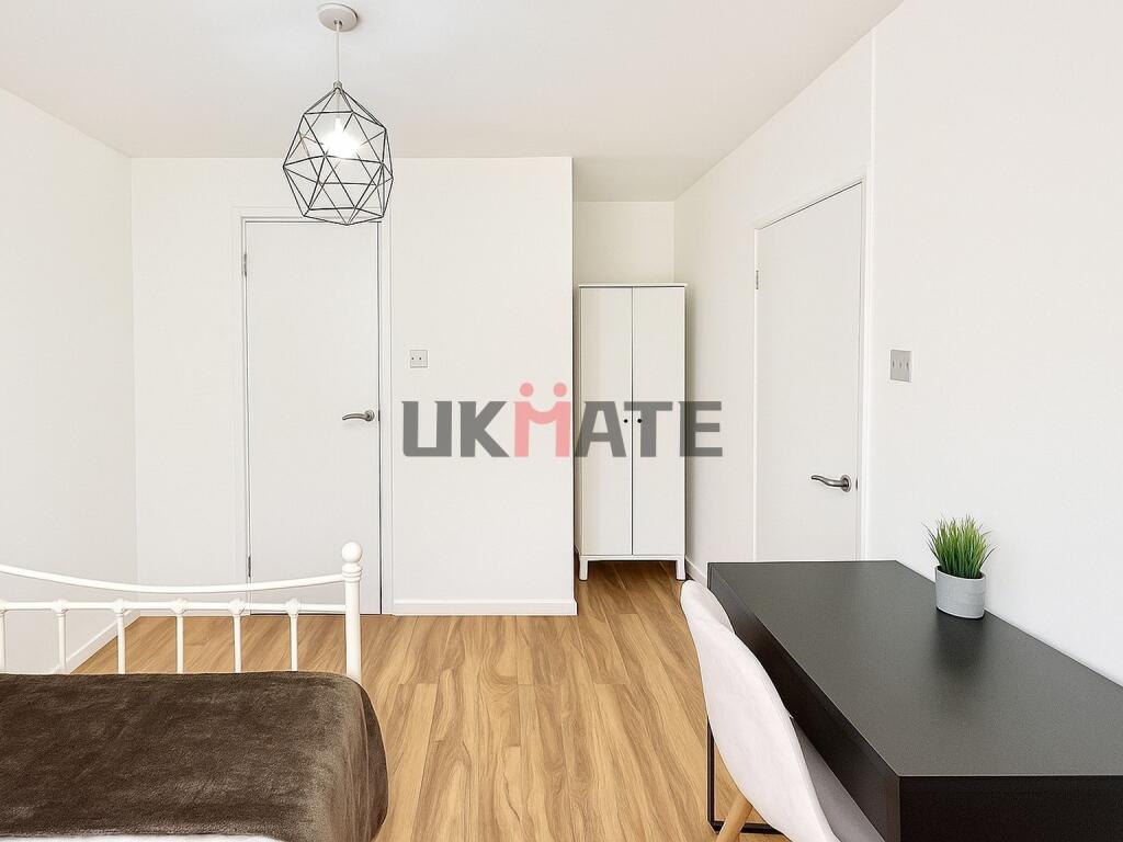 A bright and neat student bedroom featuring whi...