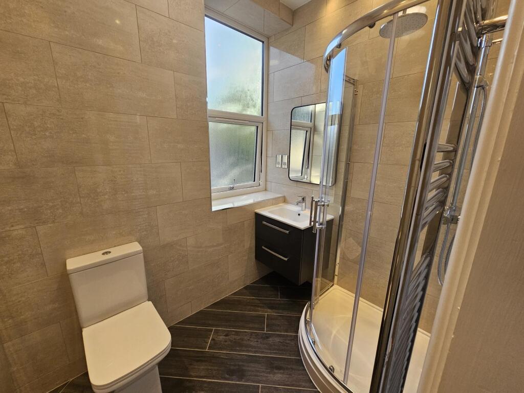 A modern bathroom suite featuring a curved glas...