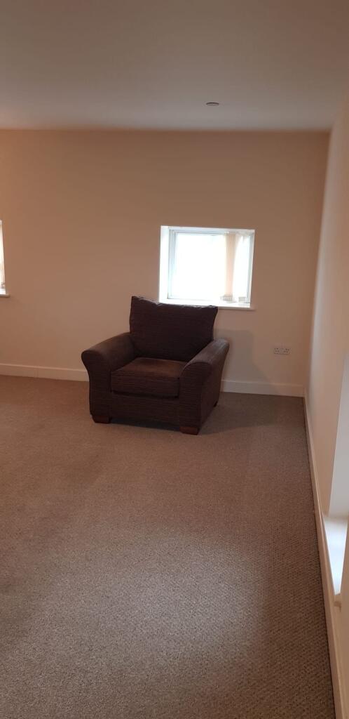 A bright living room with neutral walls and car...