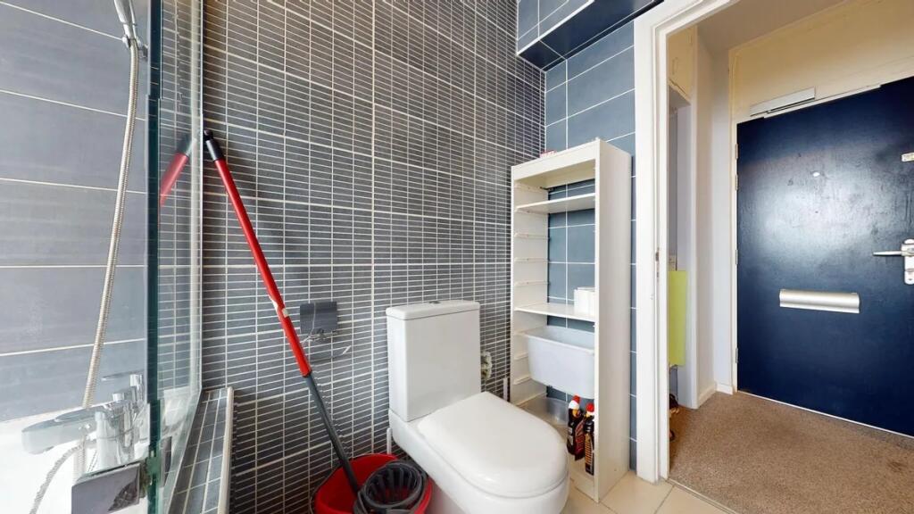 A modern single toilet room with sleek grey til...