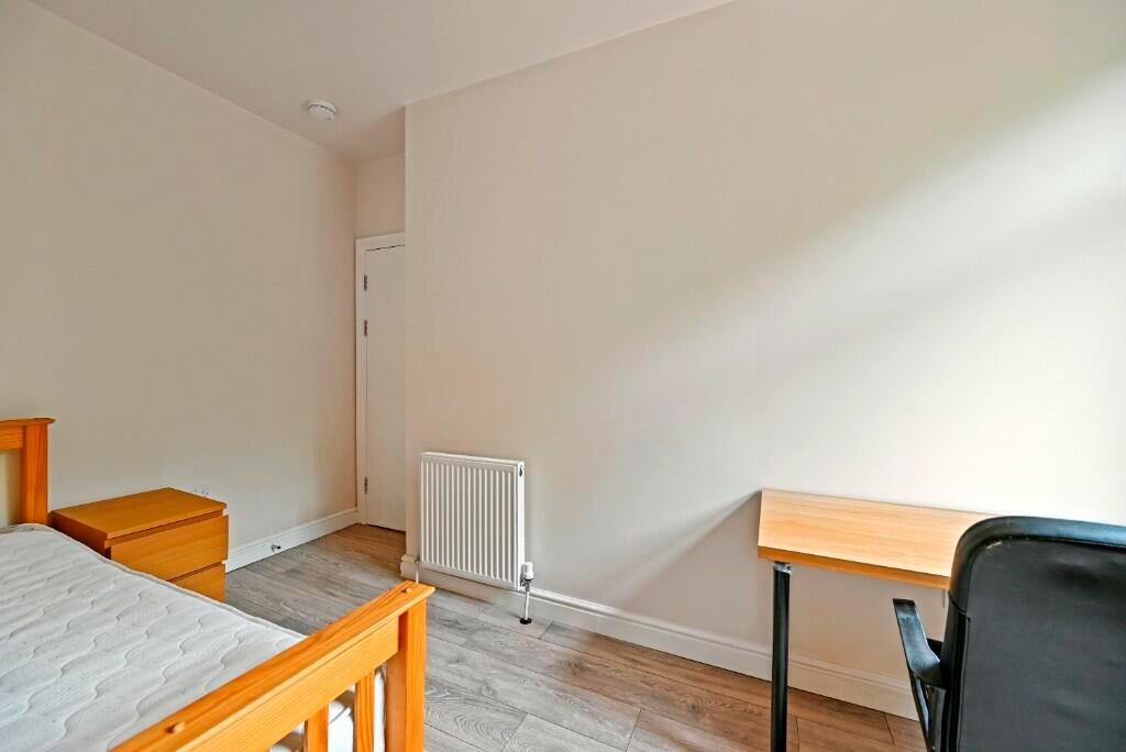 A neat and simple room featuring a wooden bed f...