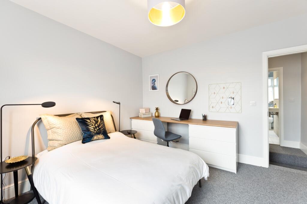 A bright and airy master bedroom featuring a co...