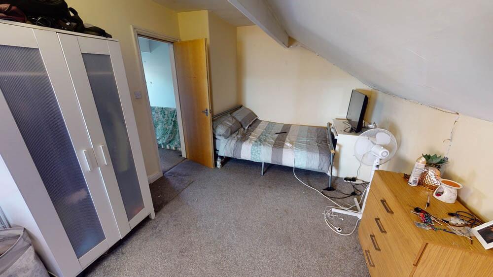 A cozy single bedroom with a sloped ceiling, fe...