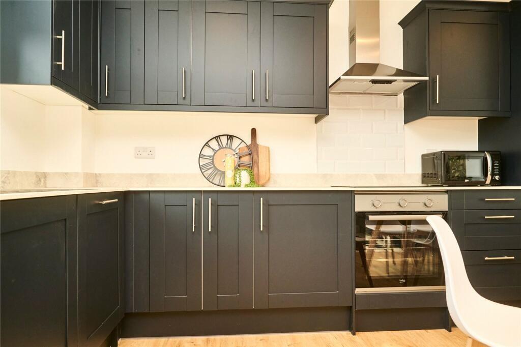Modern kitchen featuring sleek dark cabinetry, ...