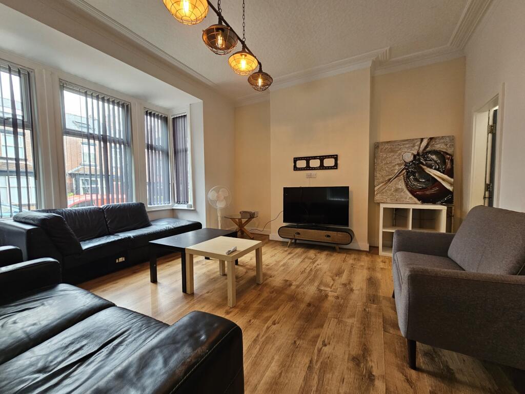 A well-lit living room featuring three sofas ar...