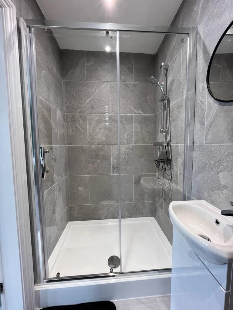 This modern bathroom features sleek grey tiles ...