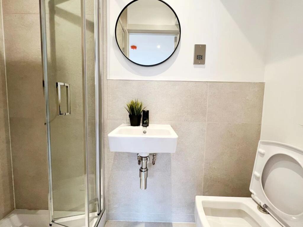 Modern bathroom featuring a compact sink, a sho...