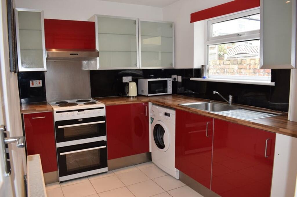 A modern kitchen featuring vibrant red cabinetr...