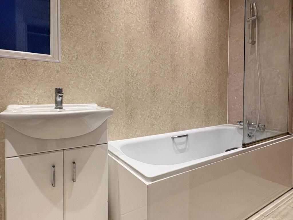 Modern bathroom with a fitted white bath and va...
