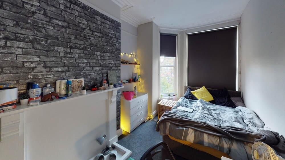 Cozy single bedroom featuring a stylish exposed...