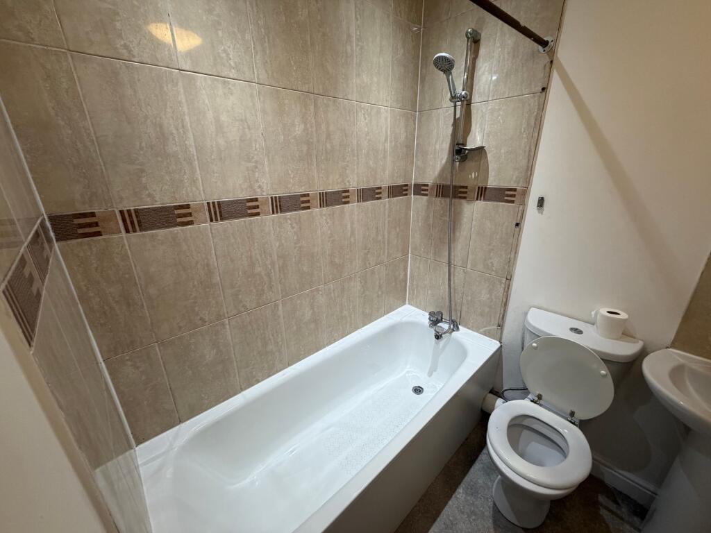 A compact bathroom featuring a bathtub with a s...