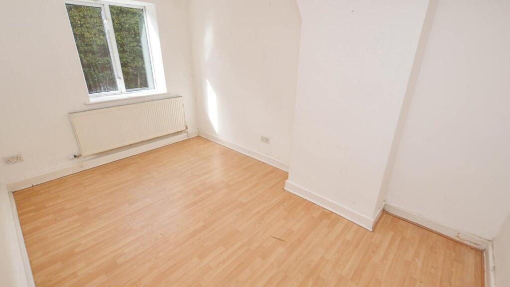 A clean, empty bedroom featuring light wood flo...