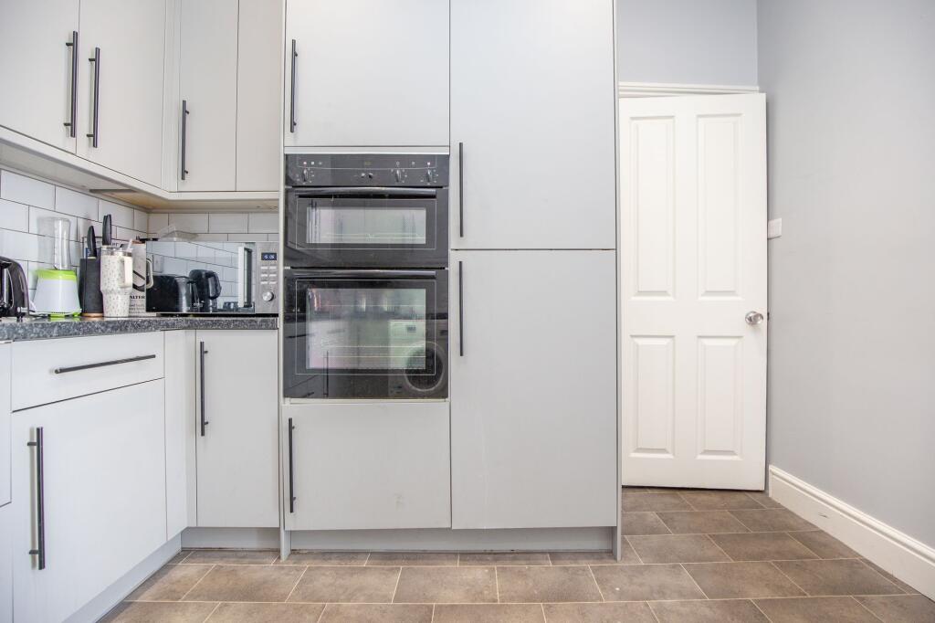 Modern kitchen with integrated double ovens, am...