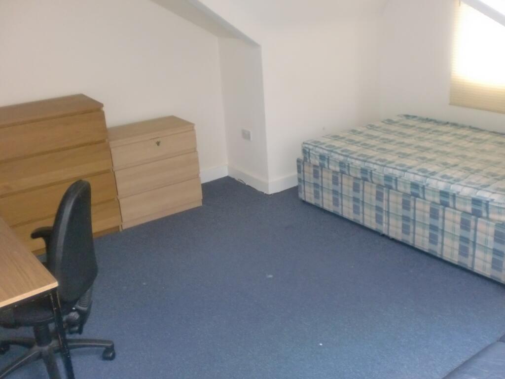 A simple, tidy student bedroom featuring a sing...