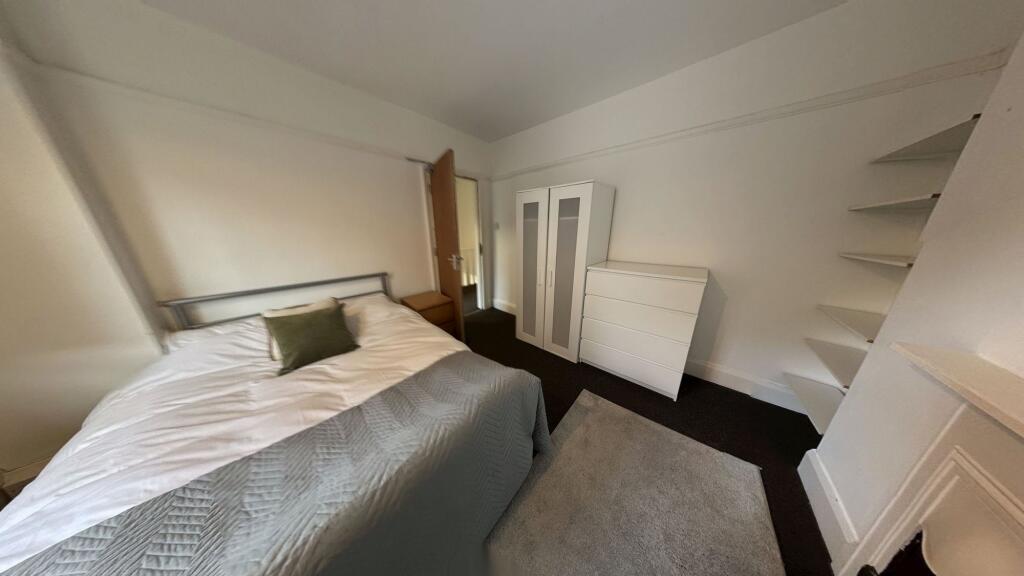 A cozy single bedroom featuring a neatly made b...